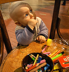 dítě u židle s pastelkami